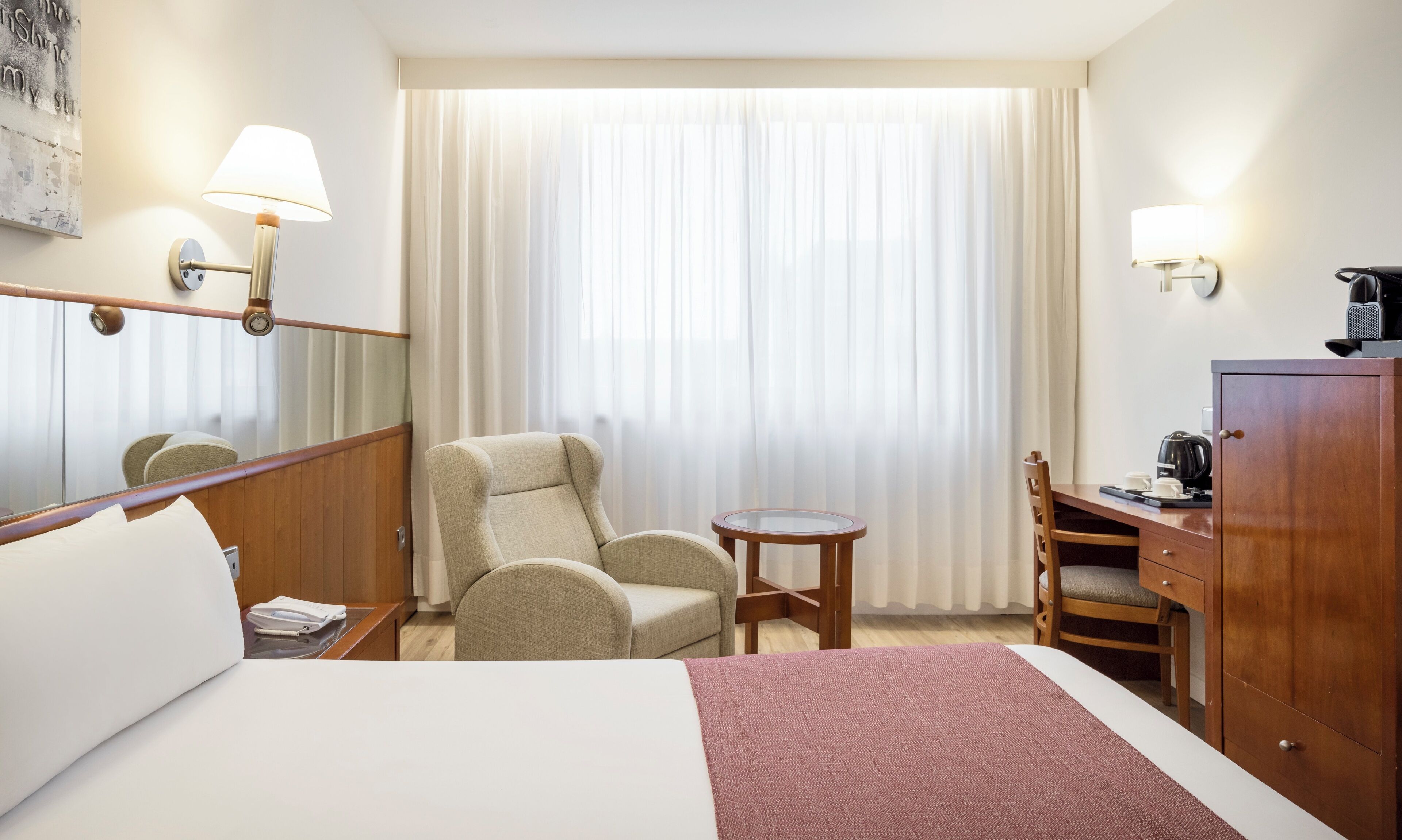 Une chambre d’hôtel comprenant un lit, une chaise, un bureau, une petite table et une armoire.