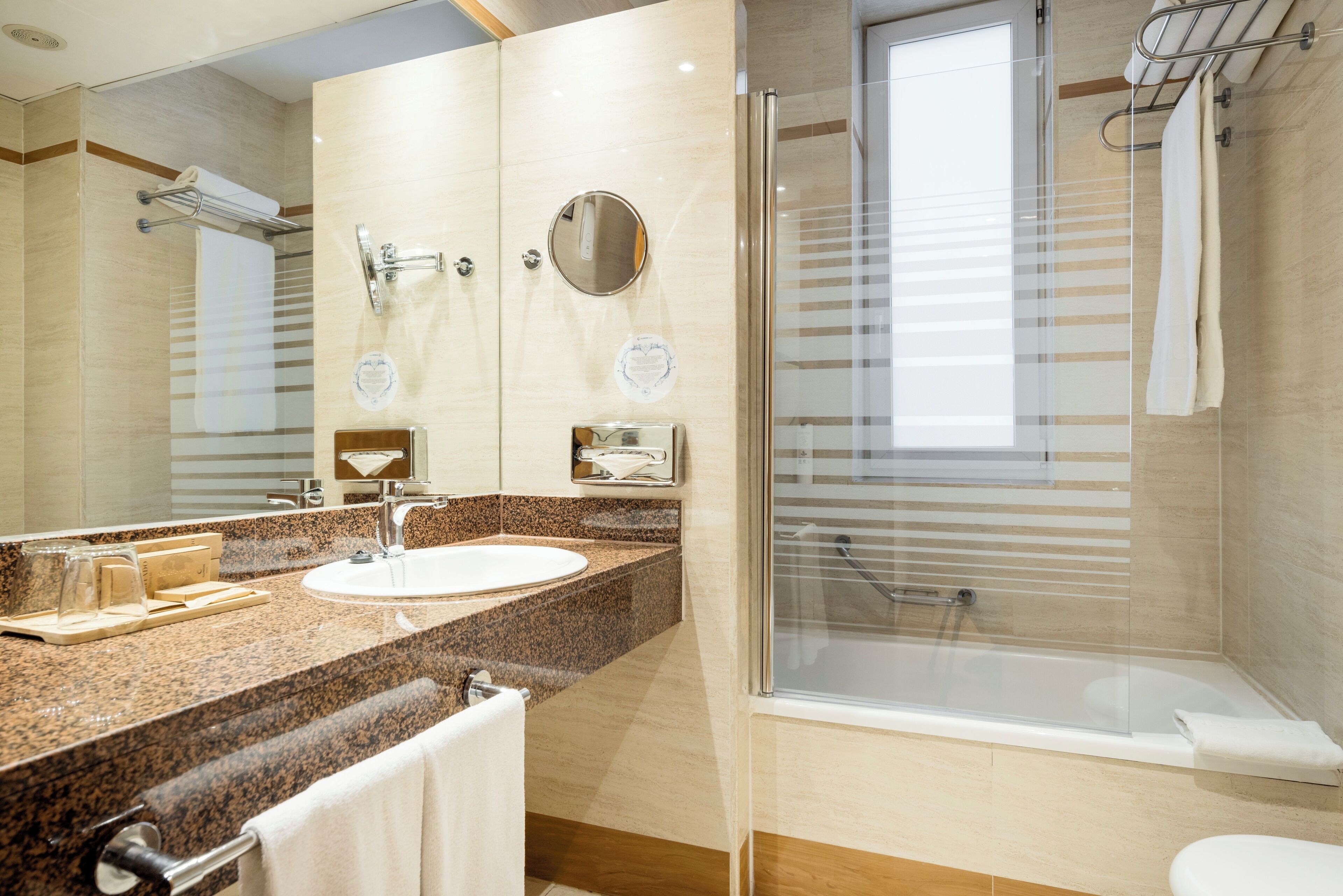 Un bagno moderno con lavabo su piano in granito, uno specchio grande, una cabina doccia in vetro e un water.