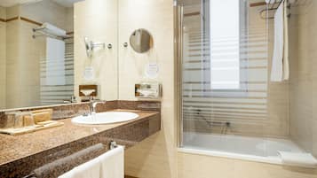 Un bagno moderno con lavabo su piano in granito, uno specchio grande, una cabina doccia in vetro e un water.