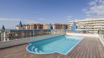 Een buitenzwembad, ligstoelen bij het zwembad