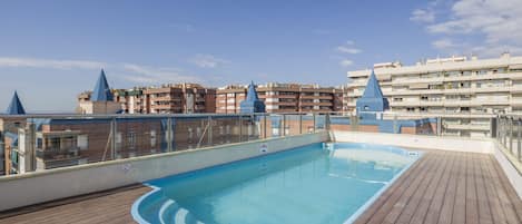 Una piscina al aire libre, sillones reclinables de piscina