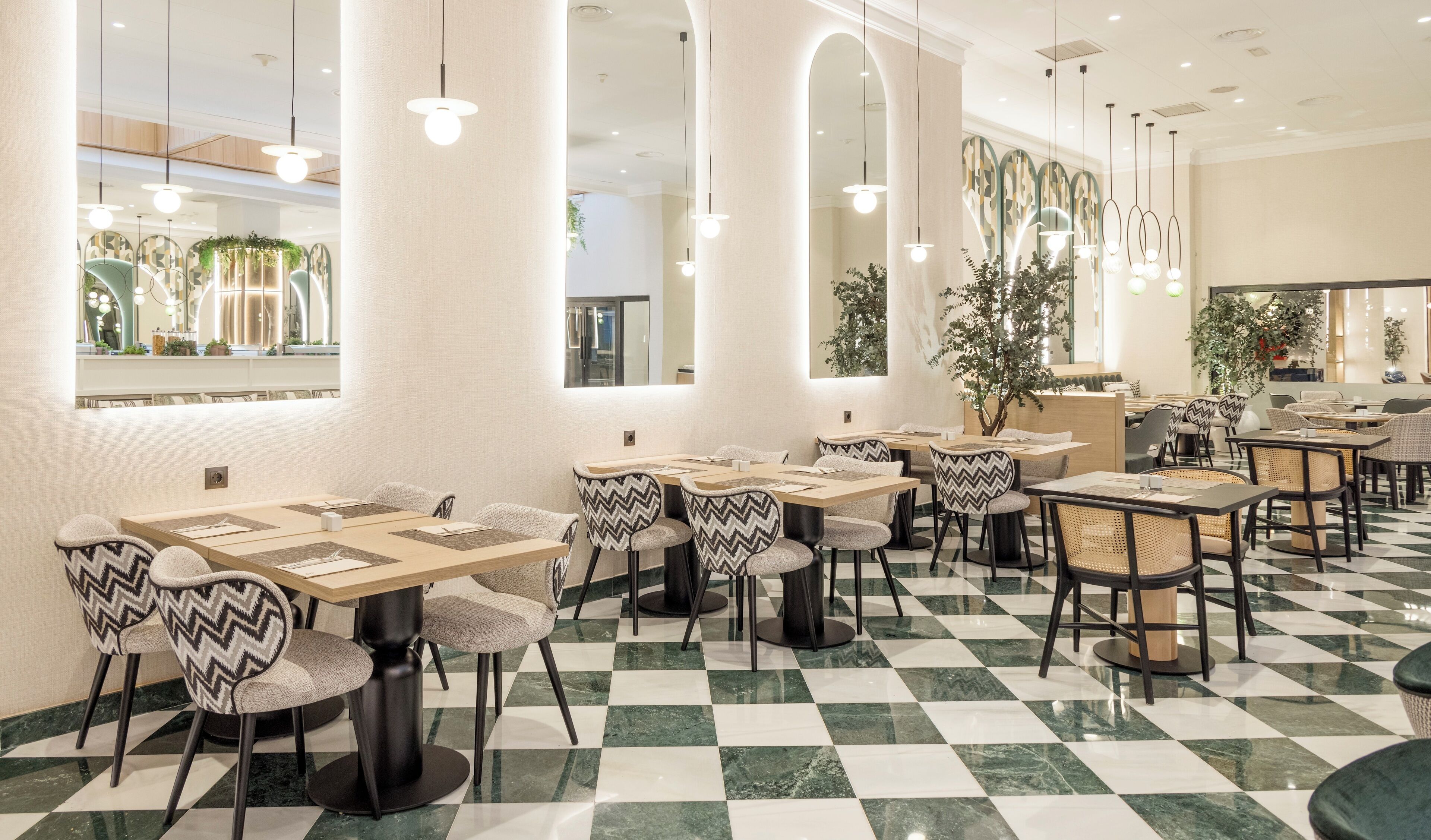 A restaurant with checkered flooring, modern furniture, and pendant lighting.