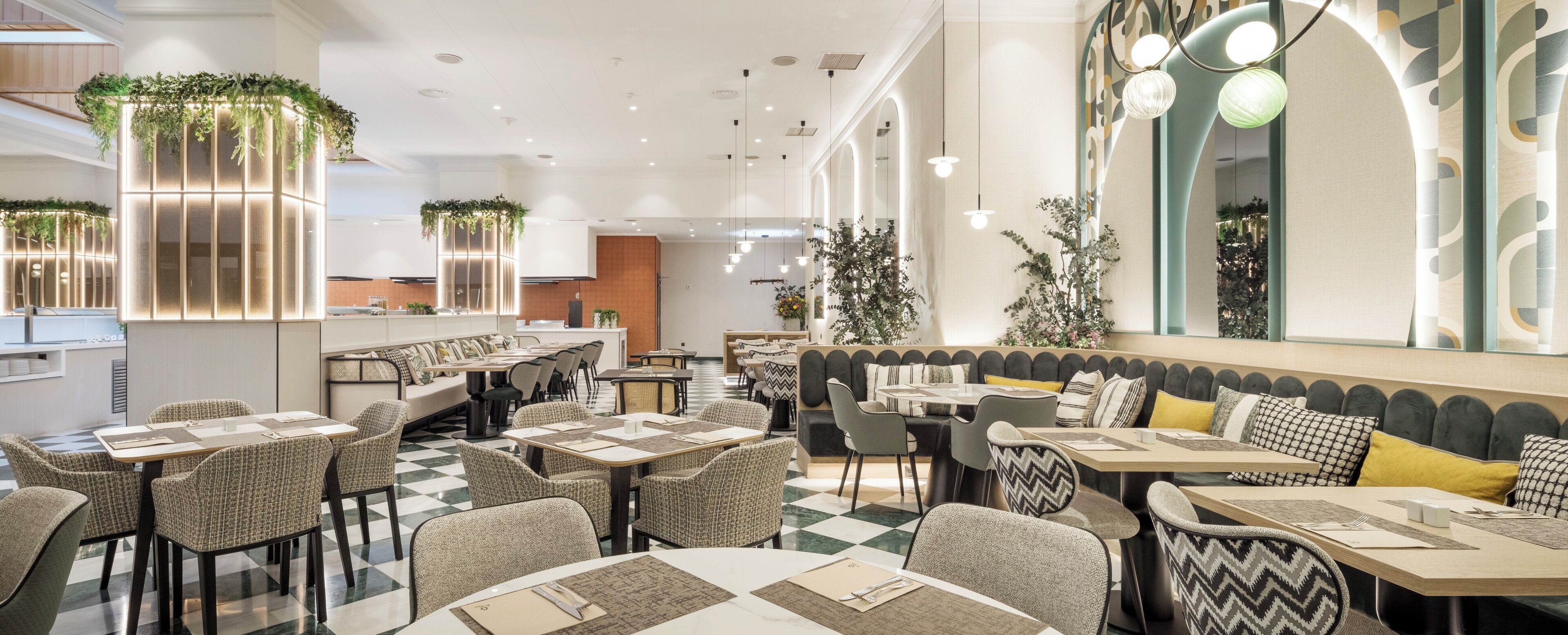 Un restaurant moderne avec un sol à carreaux, des espaces de détente avec des bancs rembourrés et un bar doté d’un comptoir.