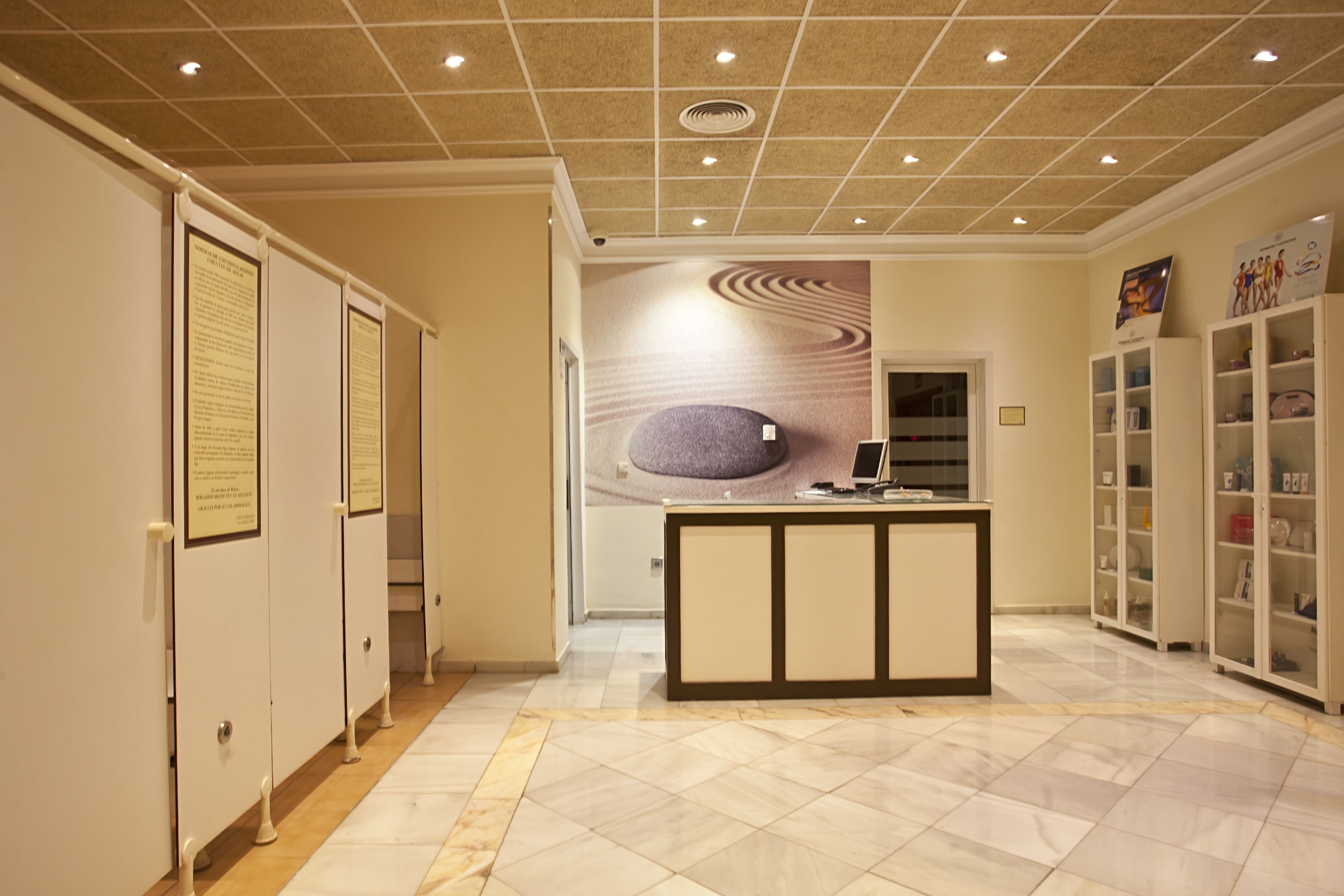 A reception area with a marble floor, a reception desk, and a wall with a circular design.