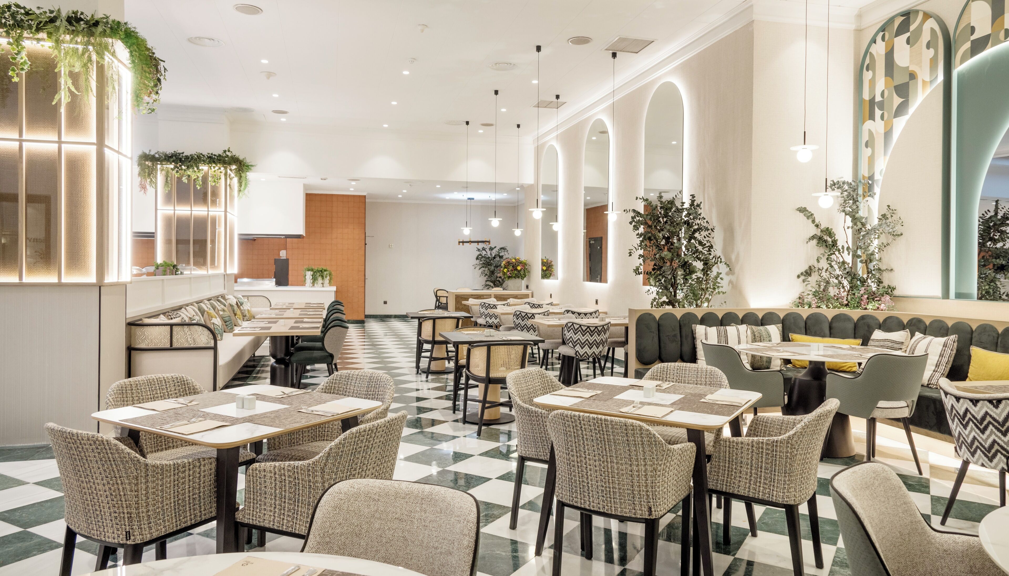En modern restaurang med rutmönstrat golv, flätade stolar och en variation av sittplatser, inklusive bord och avskilda sittgrupper.