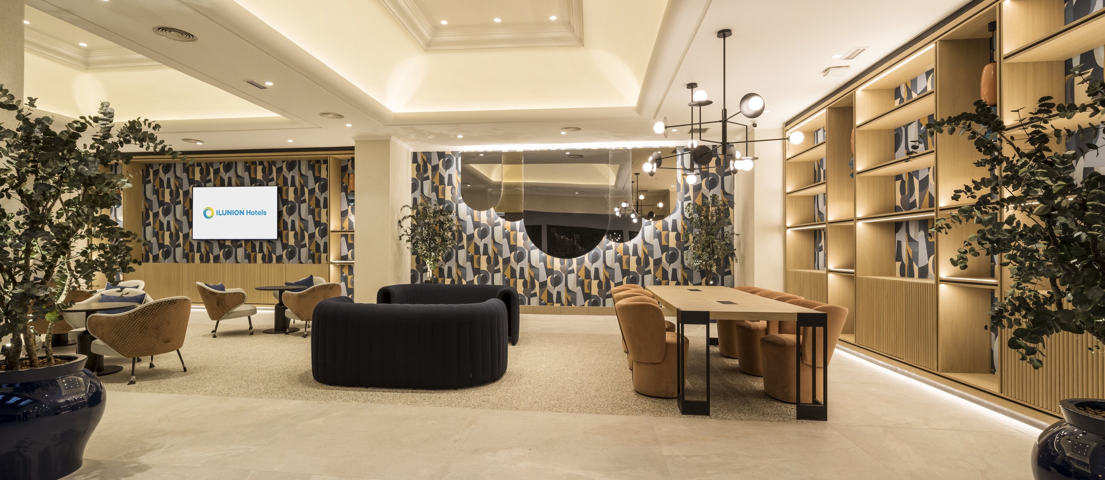 Um hall de hotel moderno com uma grande tela exibindo o nome do hotel, áreas de estar confortáveis e interior bem iluminado.