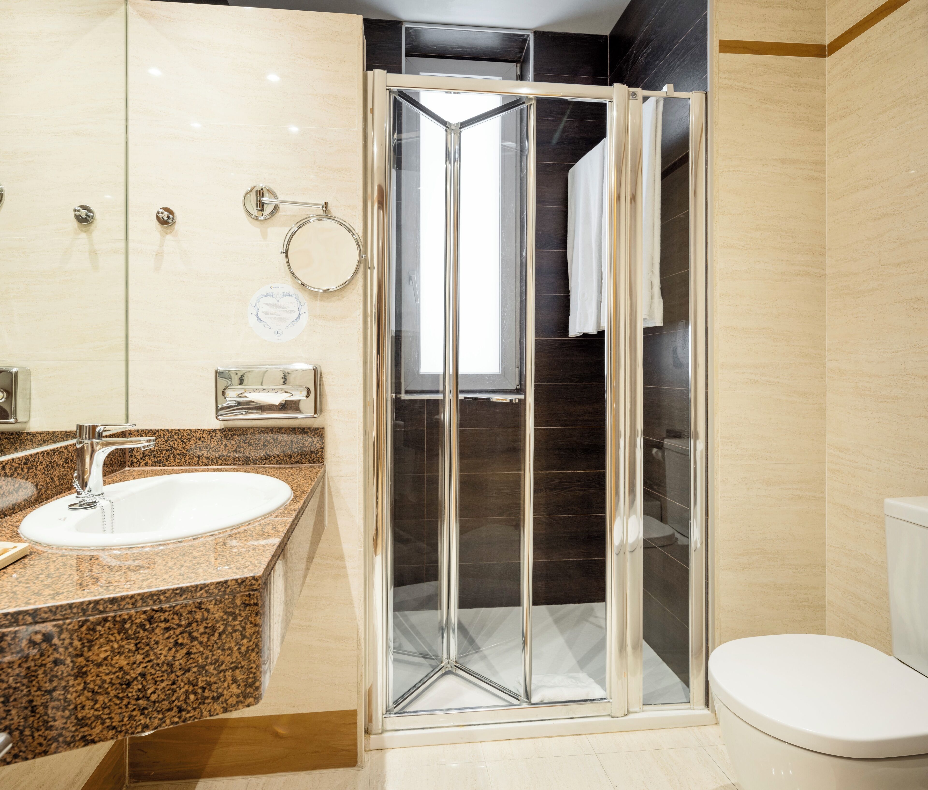 A modern bathroom with a glass-enclosed shower, a granite countertop sink, and a toilet.