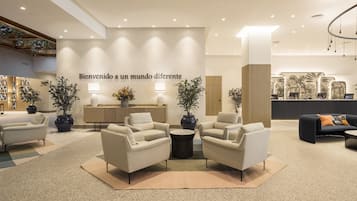 Un vestíbulo moderno con sofás, un mostrador de recepción y una pared con un mensaje de bienvenida.
