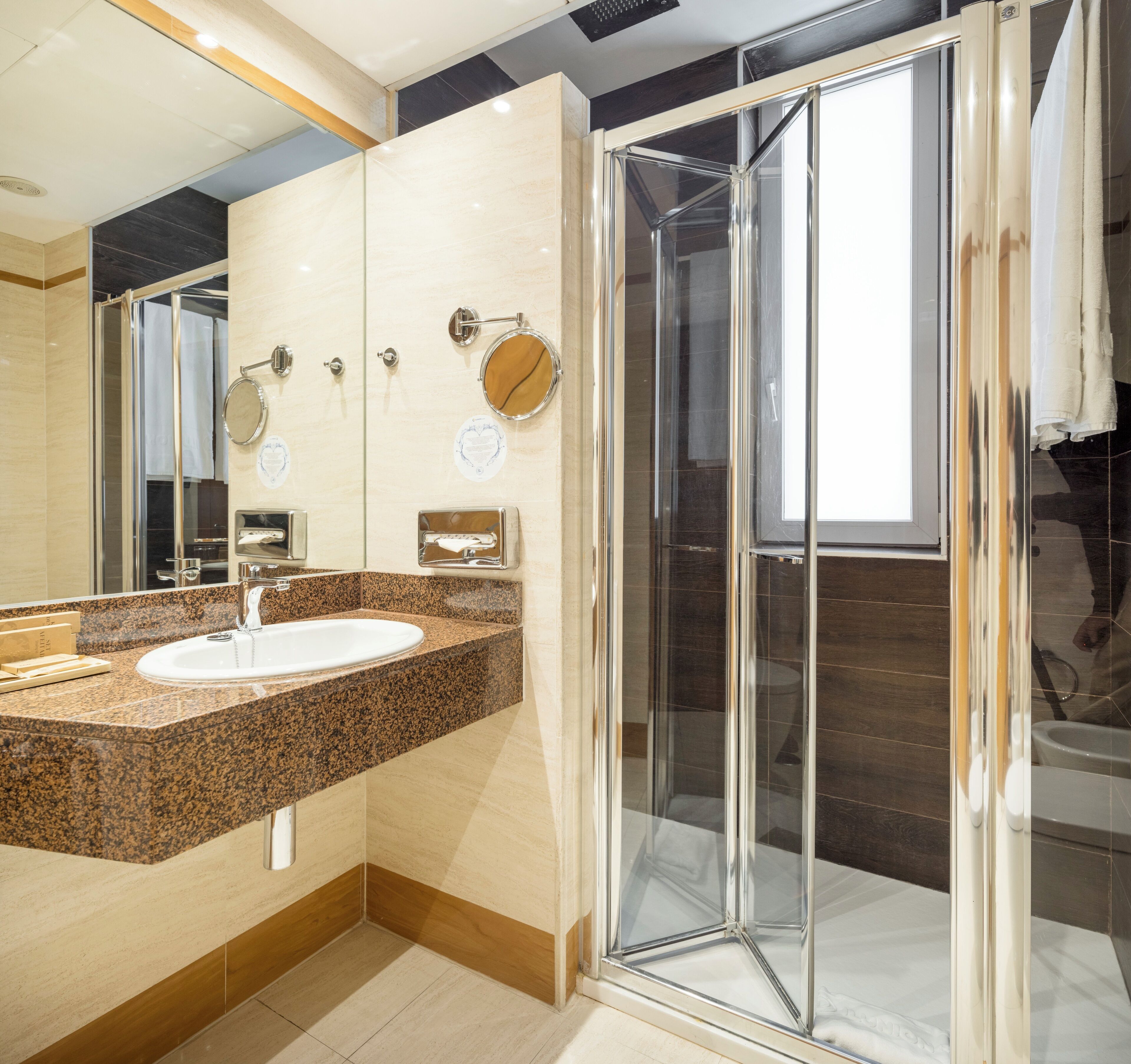 Un baño moderno con lavamanos de encimera de granito, espejo y cabina de ducha de vidrio.