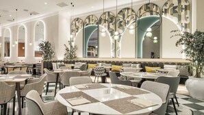 Un interior de restaurante moderno con mesas redondas, asientos acolchados y paneles decorativos en las paredes.