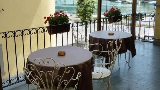 Un balcón con dos mesas redondas y sillas, barandilla y plantas en macetas.