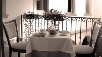 A table set for two on a balcony with a view of the building's windows.