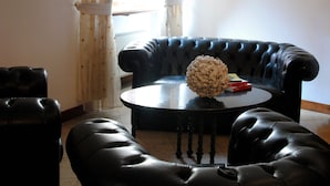 Una sala de estar con un sofá de cuero negro, una mesa redonda de centro y una esfera decorativa sobre la mesa.