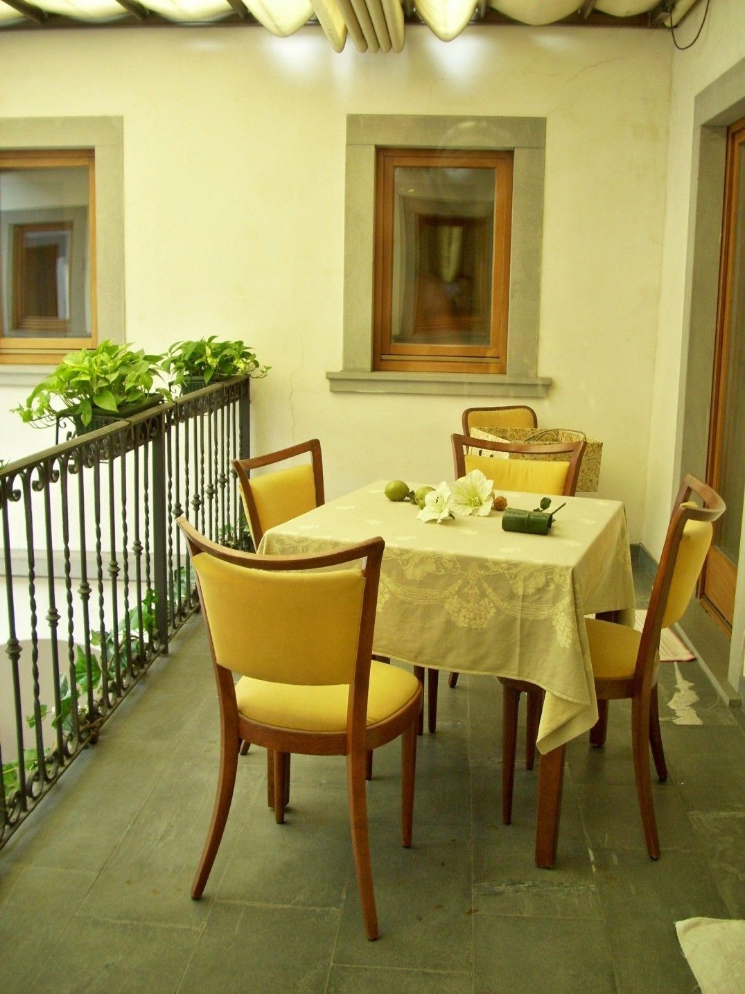 Un comedor con una mesa dispuesta para seis personas, rodeada de sillas de madera con cojines amarillos.