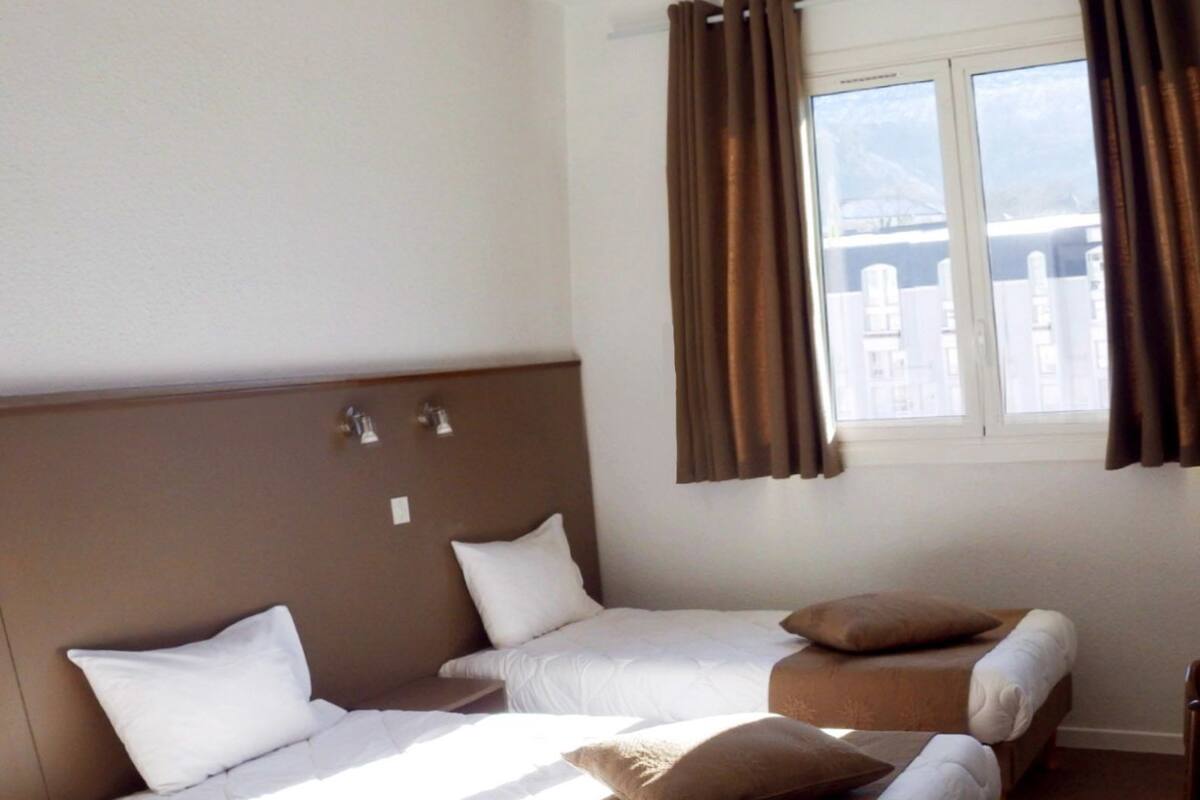 A hotel room with a large bed, two smaller beds, and a sofa.
