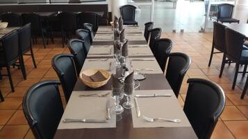 A long dining table set with multiple chairs, a central decorative item, and a bowl on the table.
