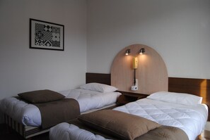 A hotel room with two beds, a wooden headboard, a wall-mounted phone, and a framed artwork. - Adonis Lourdes (Lourdes)