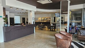 A hotel lobby with a reception desk, seating area, and a bar.