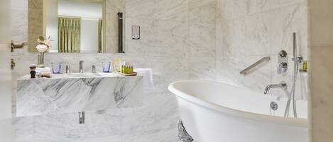 Un baño moderno con tocador de mármol, bañera independiente y un espejo grande.