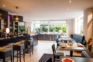 A modern restaurant with a bar area, seating for guests, and a view of the outdoors. - Hotel Borchers (Doerpen)