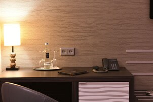 Ein Hotelrezeptionstresen mit einer Lampe, einer Wasserflasche, einem Glas, einem Telefon und einem Notizbuch.