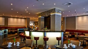 A modern restaurant with a central bar, booths, and tables with tea sets. - Artim Hotel (Berlin)