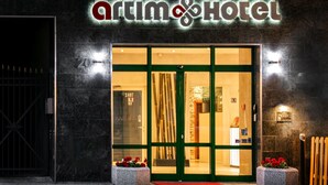 The exterior of a hotel with a large glass entrance, a name sign above, and a red carpet leading to the door. - Artim Hotel (Berlin)