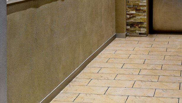 A lobby with a textured wall, a stone wall, and a tiled floor. - Artim Hotel (Berlin)