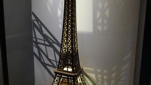 Una maqueta de la Torre Eiffel en una habitación con alfombra roja y un diseño geométrico en la pared.