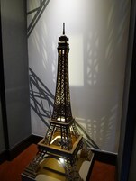 Una maqueta de la Torre Eiffel en una habitación con alfombra roja y un diseño geométrico en la pared.