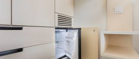 A kitchen with a built-in refrigerator, a wooden countertop, and a white wall with a light switch.