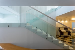 Un interior moderno con una escalera de cristal, piso a cuadros y diseño minimalista.
