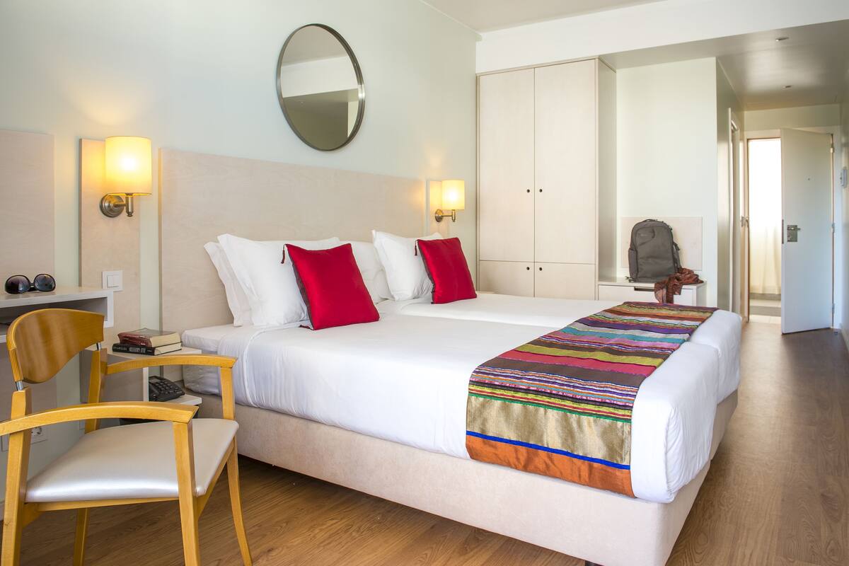 Una habitación de hotel con cama, sillón, escritorio y armario.