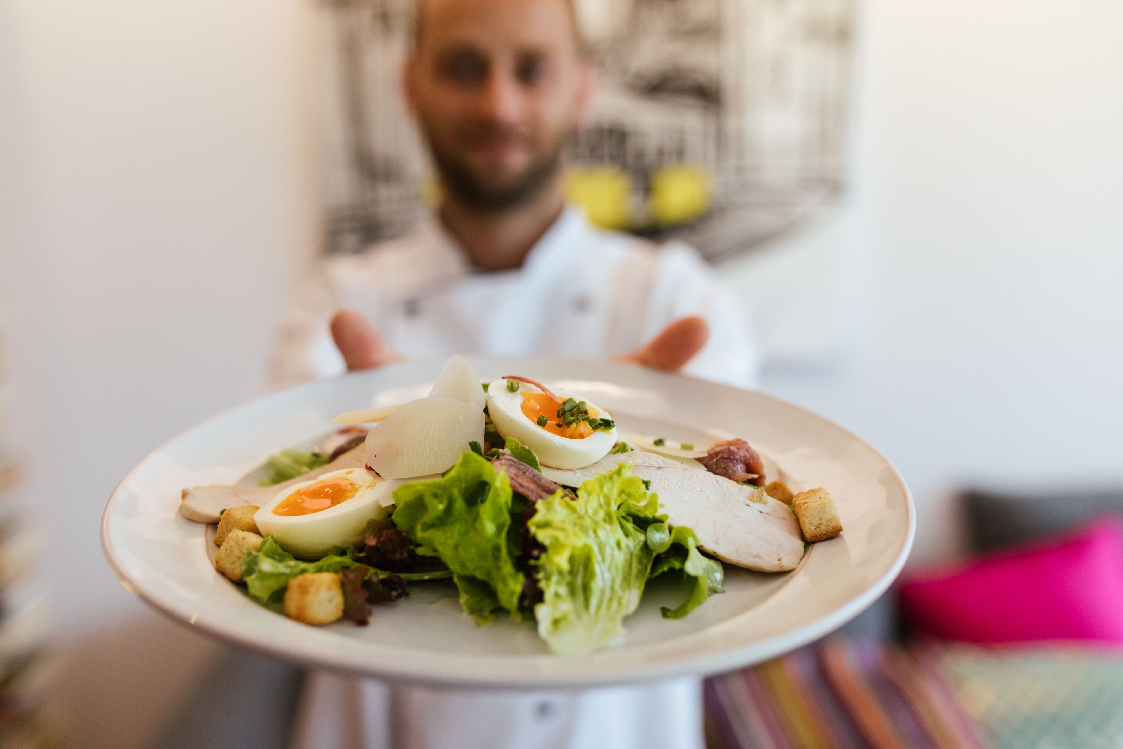 A plate of food with a chef in the background.