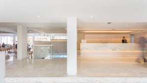 A spacious lobby with a reception desk, marble flooring, and a modern architectural design.