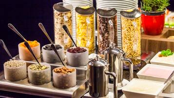 A buffet with various food items and containers, including cereals, fruits, and beverages.