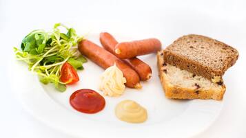 Un plato con salchichas, pan y aderezos.