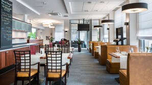 Un restaurante moderno con sillas y mesas de madera, un menú en la pizarra y una pantalla de televisión.