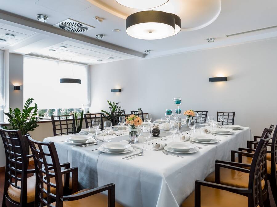 Een eetgedeelte met een lange tafel gedekt voor een maaltijd, omringd door stoelen.