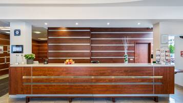 Un mostrador de recepción con detalles de madera, una pantalla digital y un frutero.