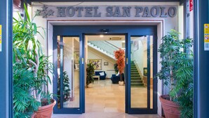 The entrance of Hotel San Paolo with a blue doormat, potted plants, and a staircase leading to the interior. - Hotel San Paolo (Naples)
