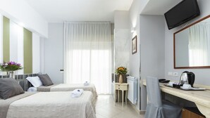A hotel room with two beds, a desk, a chair, a TV, and a window with curtains. - Hotel San Paolo (Naples)