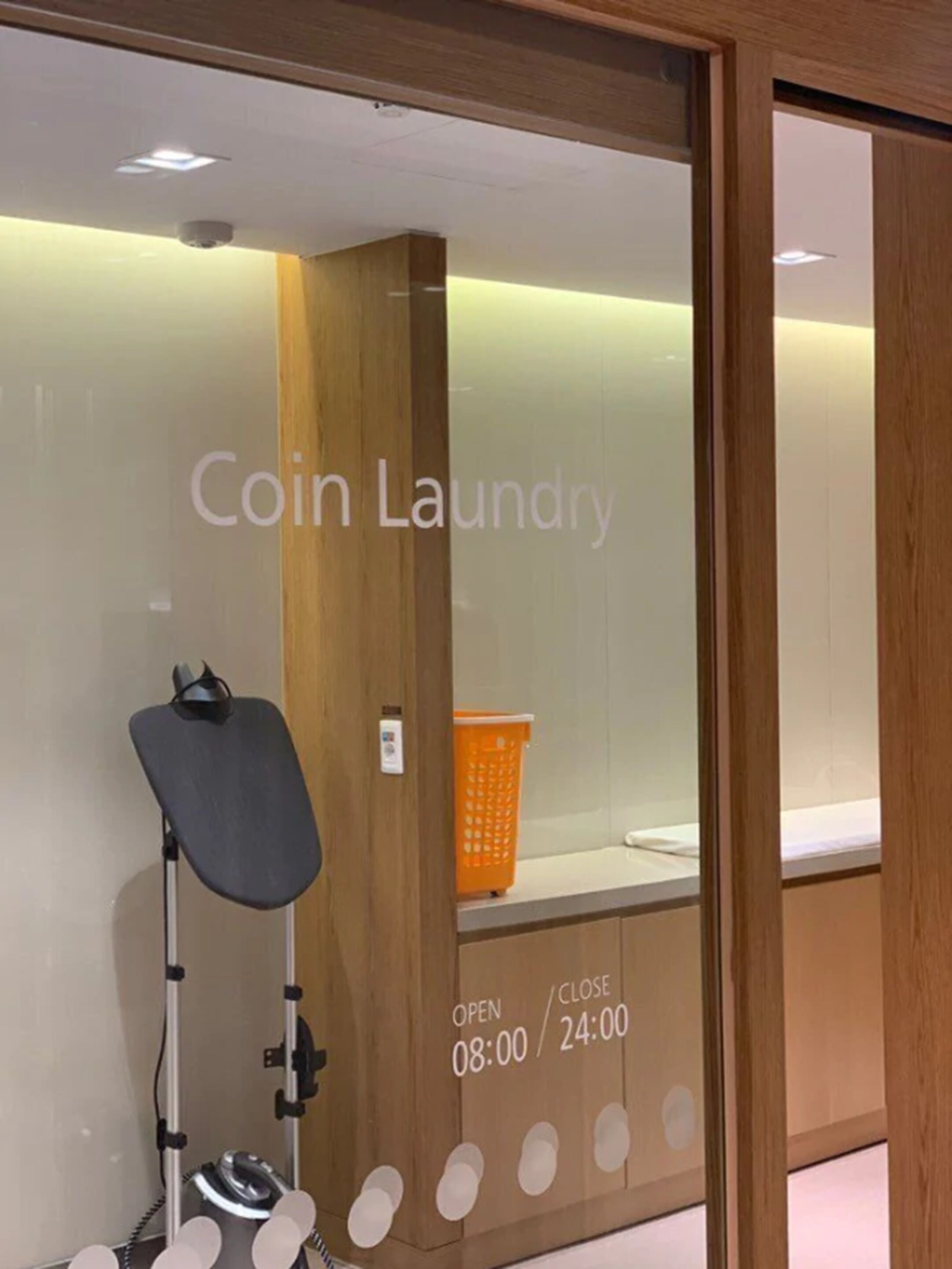 Una lavandería autoservicio con interior de madera, una cesta de ropa y una zona de doblado.