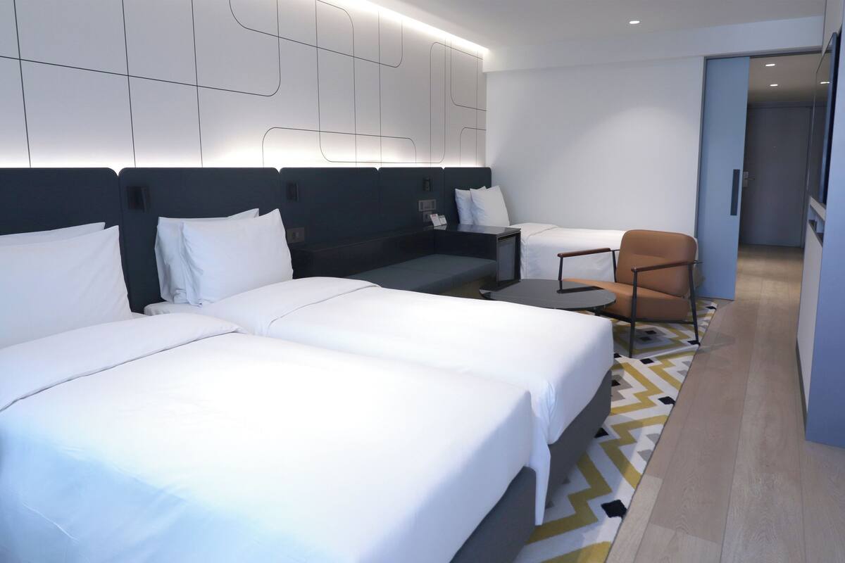 A hotel room with two beds, a desk, and a chair.