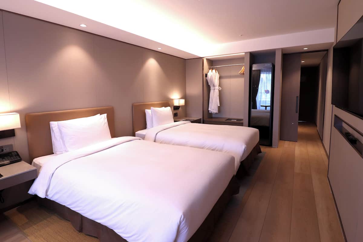 A hotel room with two beds, a TV, a robe hanging, and a walk-in closet.