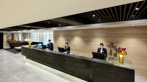 A reception desk with three staff members, a modern interior design, and a wooden accent wall.
