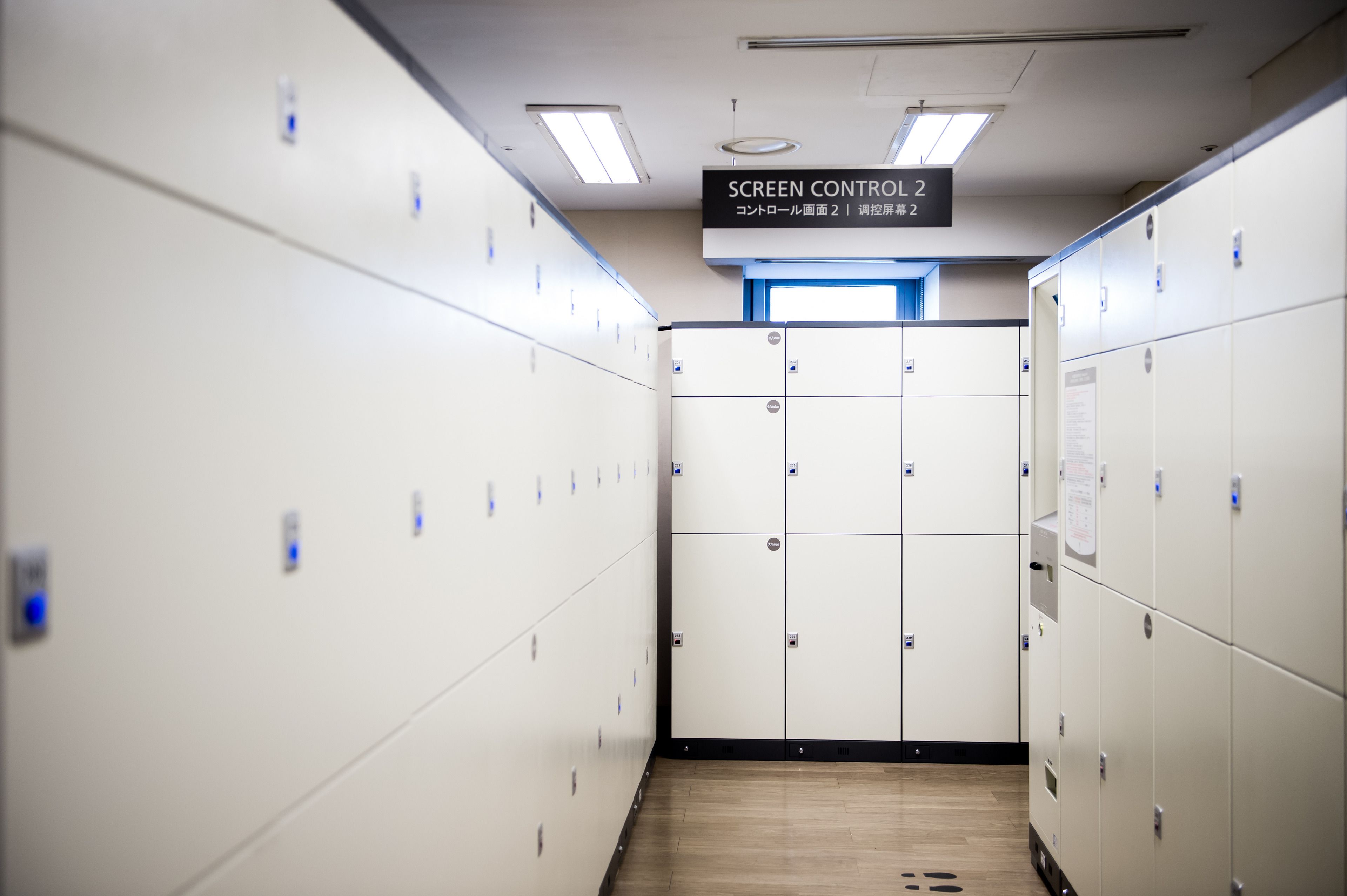 A row of white lockers with a sign above indicating 'SCREEN CONTROL 2'.