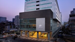 A modern hotel with a prominent 'PJ' logo, large windows, and a visible entrance.