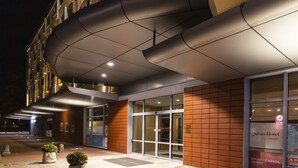 A hotel entrance with a modern design, featuring a curved awning and a glass door entrance.