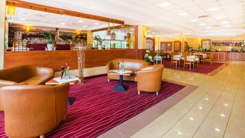 Un vestíbulo de hotel con sofás de cuero, alfombra roja y una zona de bar.